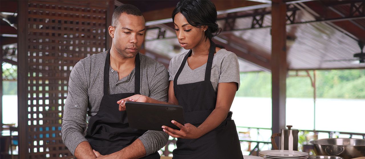 Restaurant employees looking over sales reporting tools from American PaySave