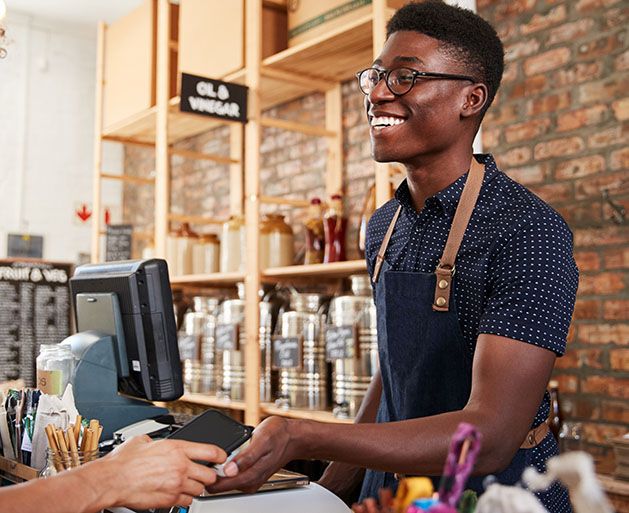 A male barista accepting card payments using American PaySave's POS systems
