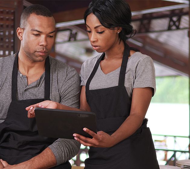 Restaurant employees looking over sales reporting tools from American PaySave